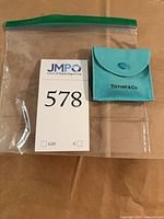 Tiffany & Co. suede pouch in clear bag beside lot tag