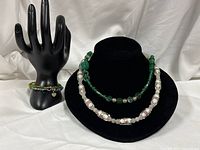 Two necklaces on bust, one pink Murano bead, one green glass bead; bracelet on hand display