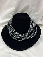 Necklace displayed on bust showing five strands of black pearls