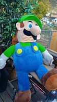 Full Luigi plush laid on bench showing overall size and entire figure