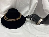 Wide shot showing bracelet on hand display and necklace on velvet bust