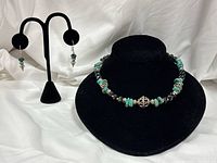 Necklace displayed on bust with matching earrings on stand