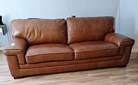 Front view of cognac brown three-seat sofa with dark piping