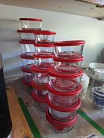 Stacks of clear glass bowls with red lids showing quantity and sizes