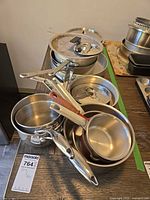 Stacked assortment of stainless saucepans and lids on table