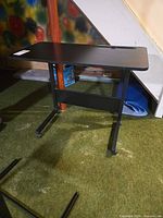 Full view of black rolling C-shape side table on green carpet