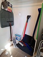 Overall lot showing rubber mat with tag, manual foot pump, snow brushes, wiper blades, inflator box