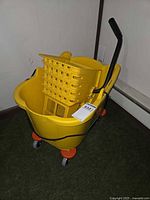 Full view of yellow mop bucket on casters with wringer inserted