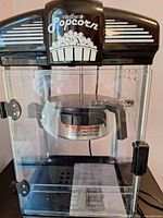 Front view showing West Bend Popcorn branding, clear housing, kettle inside