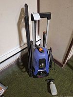 Full view of pressure washer with wand, hose and detergent bottle