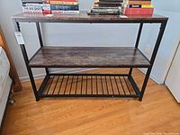 Front view of console table showing three tiers and books used as scale items