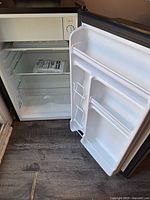 Open Hisense mini fridge showing interior, glass shelf, freezer compartment, door bins