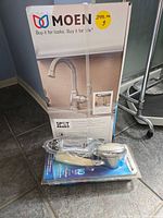 Boxed Moen faucet and sealed Waterpik shower head