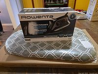 Rowenta DW23 iron retail box atop sealed tabletop ironing board