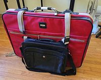 Red Samsonite suitcase with black laptop briefcase attached, floor view