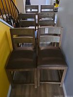 Six wooden ladder-back dining chairs lined in two rows
