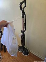 Full view of Shark steam mop standing upright with bag of extra pads