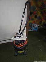 Shop-Vac canister vacuum with hose, cord coiled, papers on top