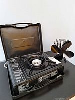 Overall view of stove in open carry case alongside Voda fan