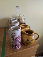 Side view showing 4 Amstel mugs, 2 Glen Eagle jugs, 2 Bermuda steins with pewter lids