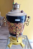 Front view showing floral design, spout, handles and lid