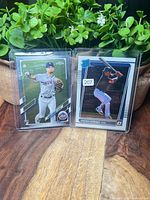 Both baseball cards in holders on tabletop