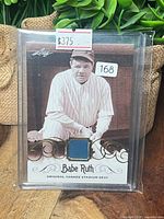 Front view of Leaf Babe Ruth relic card in holder showing price sticker and lot sticker