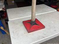 Close side view of tamper head attached to wooden handle, showing size and gussets