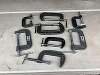 All eight C-clamps laid out showing sizes and condition