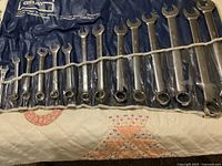 Full view of 14-piece wrench set in roll pouch on bed