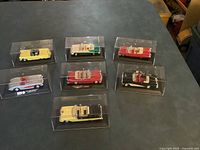 Seven die-cast convertible cars in individual acrylic cases