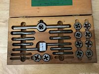 Open wooden box showing interior layout with taps, dies, tap wrench and die stock in routed wooden tray