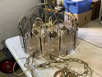 Chandelier on table showing overall form, brass frame, smoked glass panels, chain and canopy