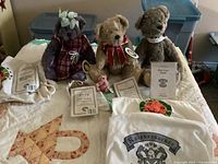 Four teddy bears with tags and cloth sleeves displayed on bed