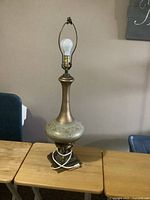 Full view of tall glass and metal table lamp on table