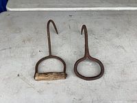 Two cast iron meat hooks side by side on table