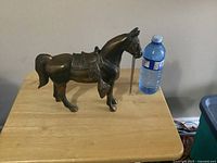 Right side profile of copper horse figurine beside water bottle for scale