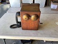 Front view showing wood cabinet, brass bells, handset, side crank