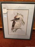 Full view of framed cross-stitch showing bird image, frame and lot tag