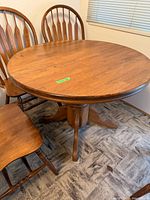 Round wood pedestal dining table with three chairs