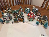 Full set of village buildings, trees, snow, and lights displayed on table
