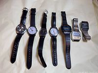 Group shot of seven men's wristwatches with straps and bracelets displayed