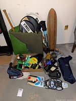 Overall view of lot with skateboard, golf mat, rackets, trekking poles, accessories