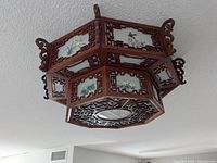 Overall view of octagonal wooden ceiling light with painted glass panels installed on ceiling