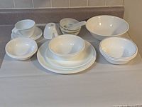 Entire lot on countertop showing plates, bowls, cups, serving bowl, mortar, pestle