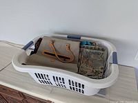 Laundry hamper containing beige purse and tapestry tote