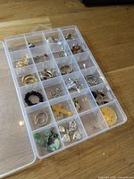 Overall view of clear compartment box with assorted jewelry pieces