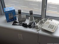 All three telephones, accessories and box on windowsill