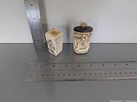 Both carved bone pieces beside rulers for scale