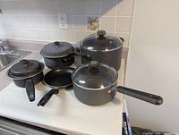 Group shot of four pots with lids, one saucepan with lid and one skillet